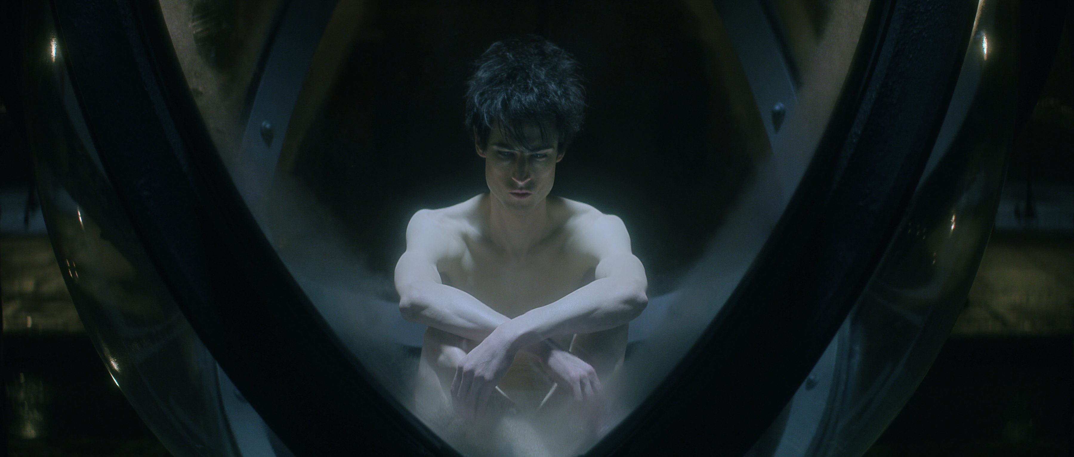 Tom Sturridge as Dream of the Endless in The Sandman, sat in the glass cage that is his prison