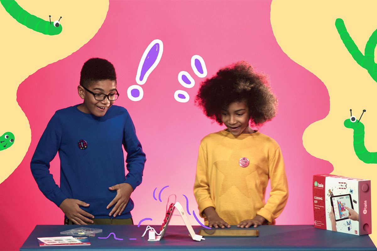 Two kids excitedly playing with a project on a table, with illustrations surrounding them.