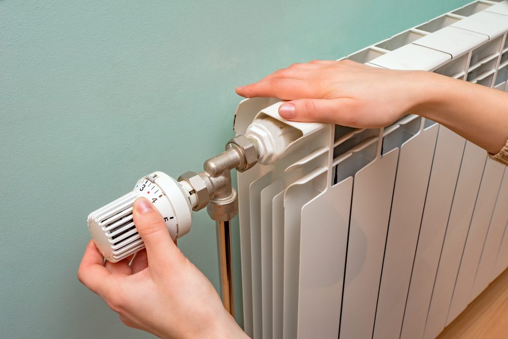 person adjusting radiator valve