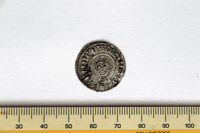 A silver coin discovered at Lyminge, Kent, with ruler for scale