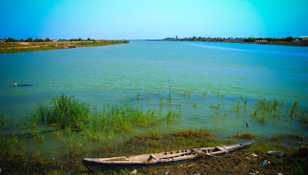 A blue green river called Shatt al-Arab at the  Euphrates and Tigris confluence.