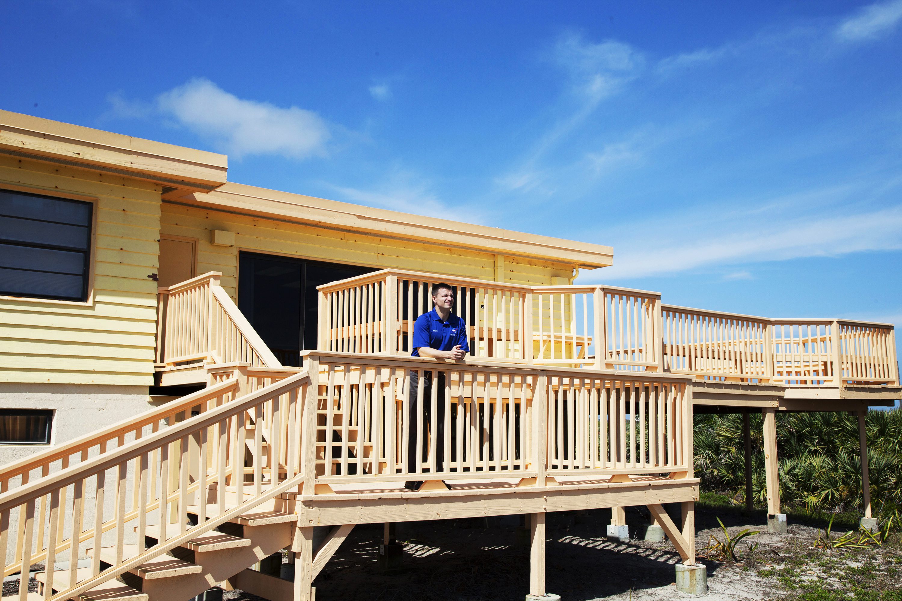 the decking of the beach house is visible in this picture with Andrew Morgan on the landing of the staircase that gets from the second floor to the beach