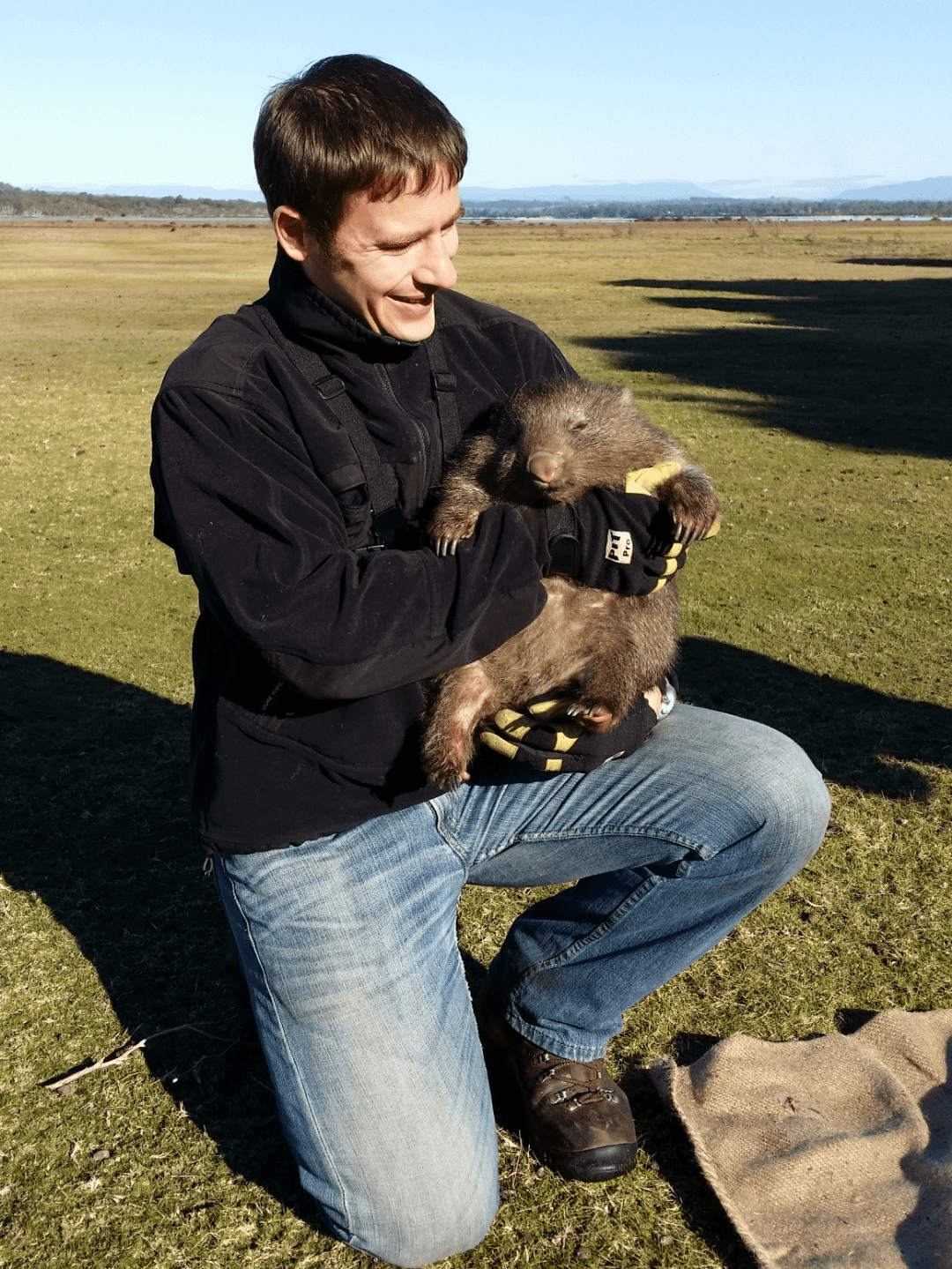 Scott carver holding up a young wombat who has no idea why he is famous