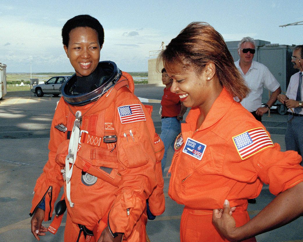 Jemison and McDougle are smiling as they both walk in the foreground