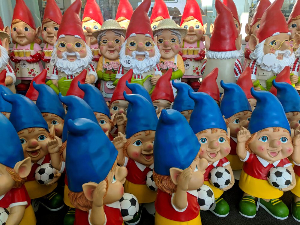 A variety crowd of colourful garden gnomes for sale in a supermarket