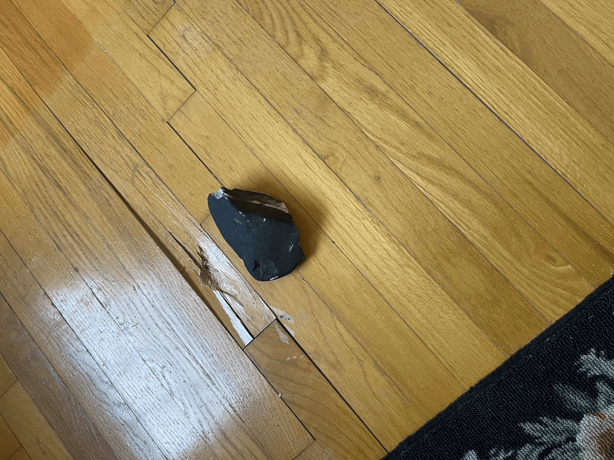 The Hopewell meteorite next to the piece of the floor it damaged