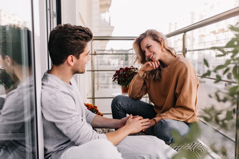 Man and woman sitting on a balcony having a conversation