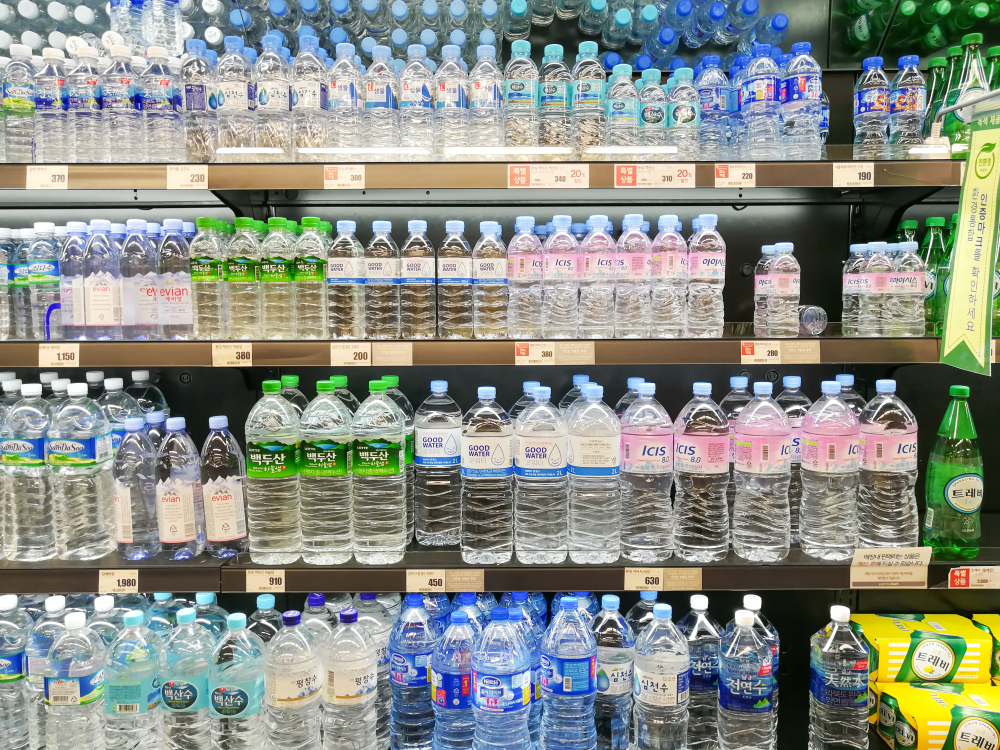 Four supermarket fridge shelves of various brands of bottled water