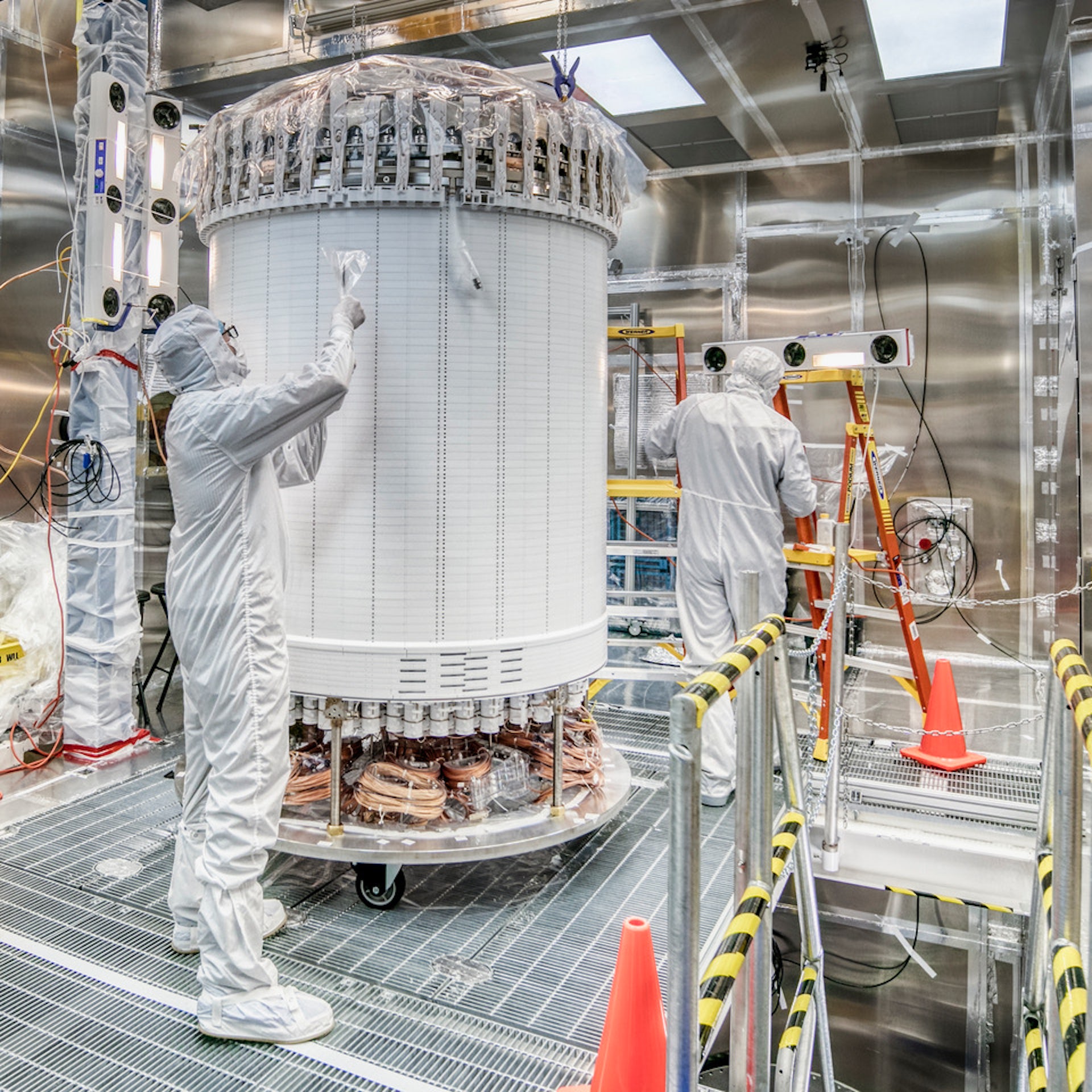 Two people in white safety gear work on the inner detector of LZ