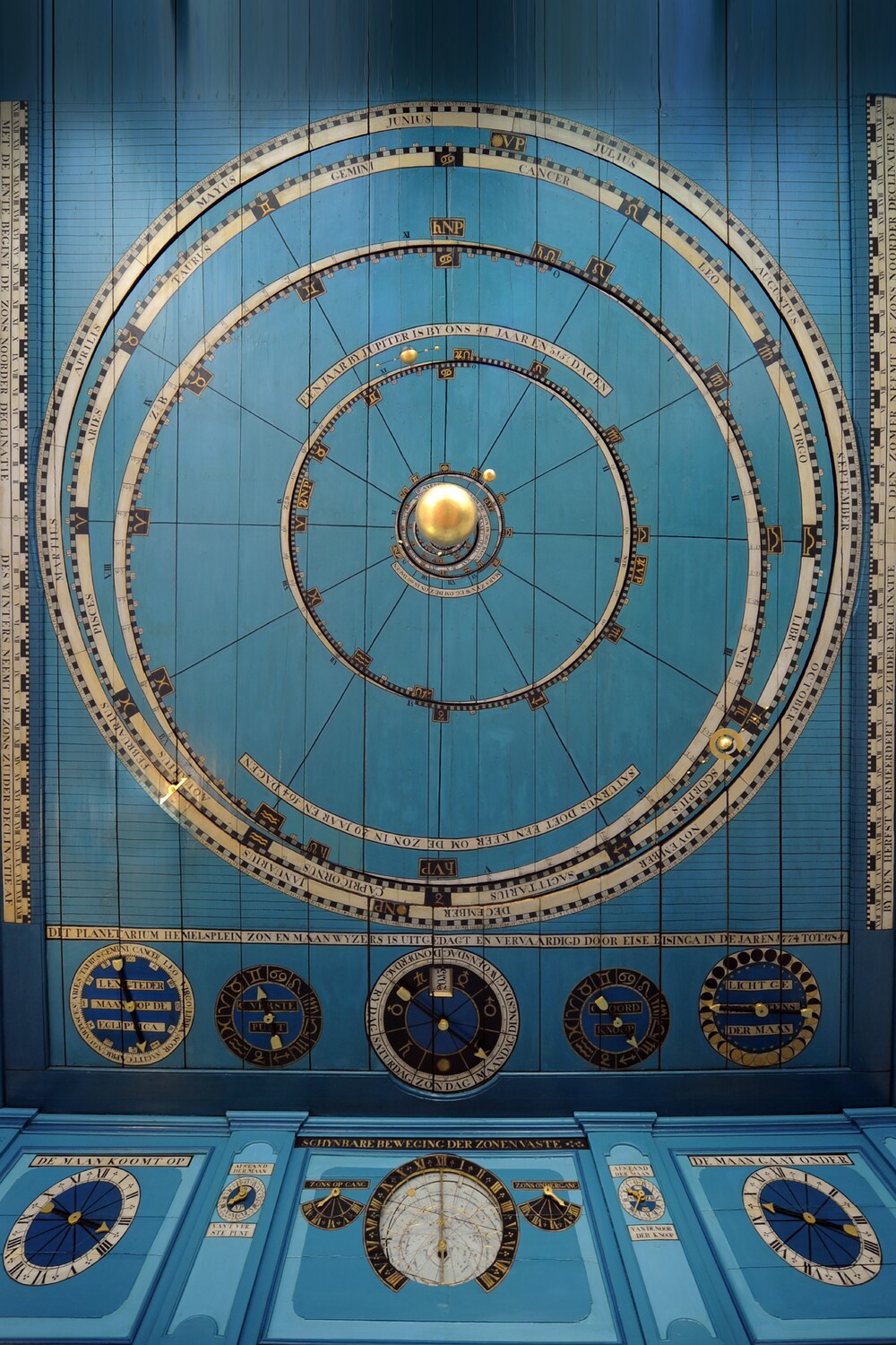 Gold colored model of the solar system on a blue wooden ceiling.