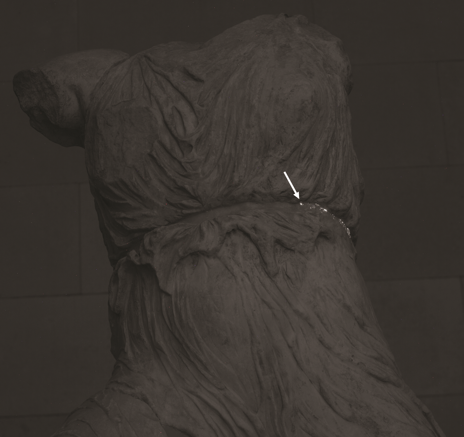 headless, armless statue in sepia tone with bright white spots and an arrow showing where samples were taken