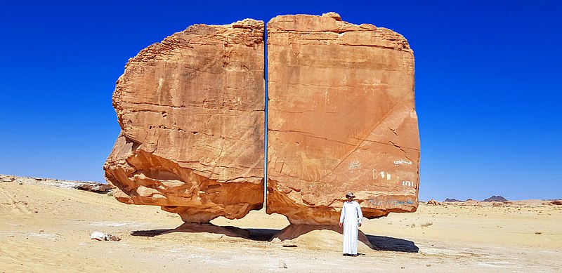 Al Naslaa Rock with a man standing infront