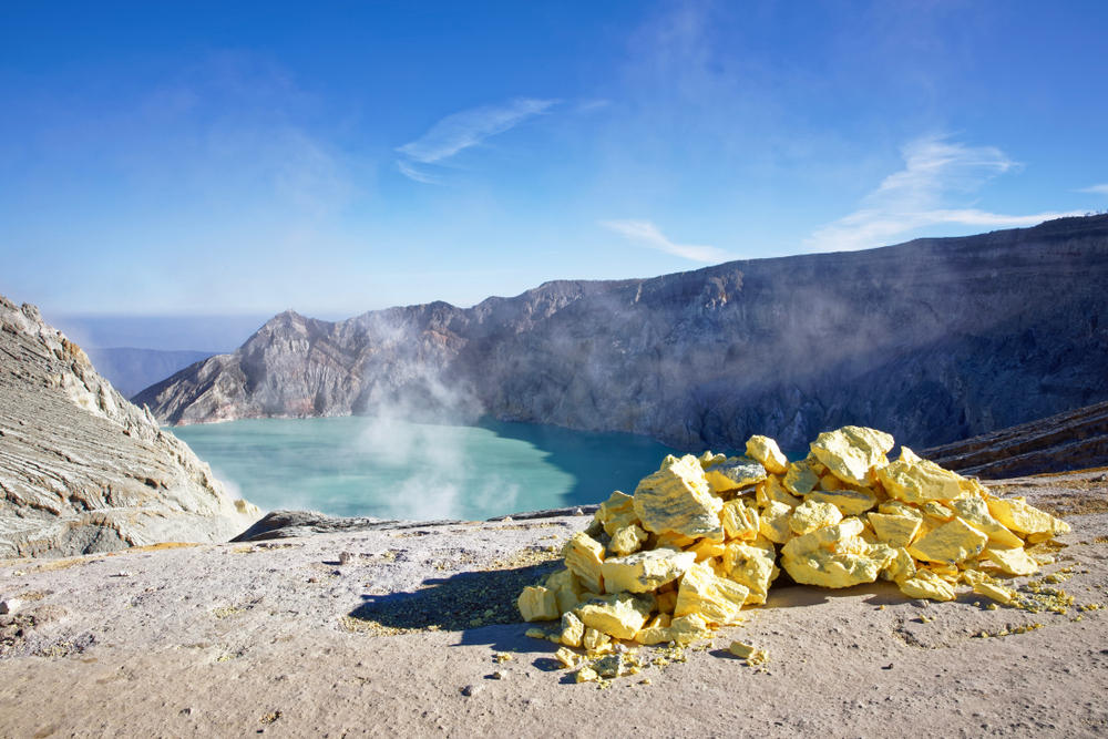 The sulfuric lake of Kawah Ijen volcano in East Java with sulfur stone in foreground, Indonesia