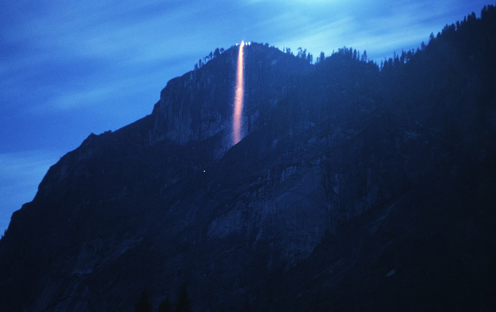 A single pour of gold and red falls down a cliff which is otherwise blue and. Long exposure photograph