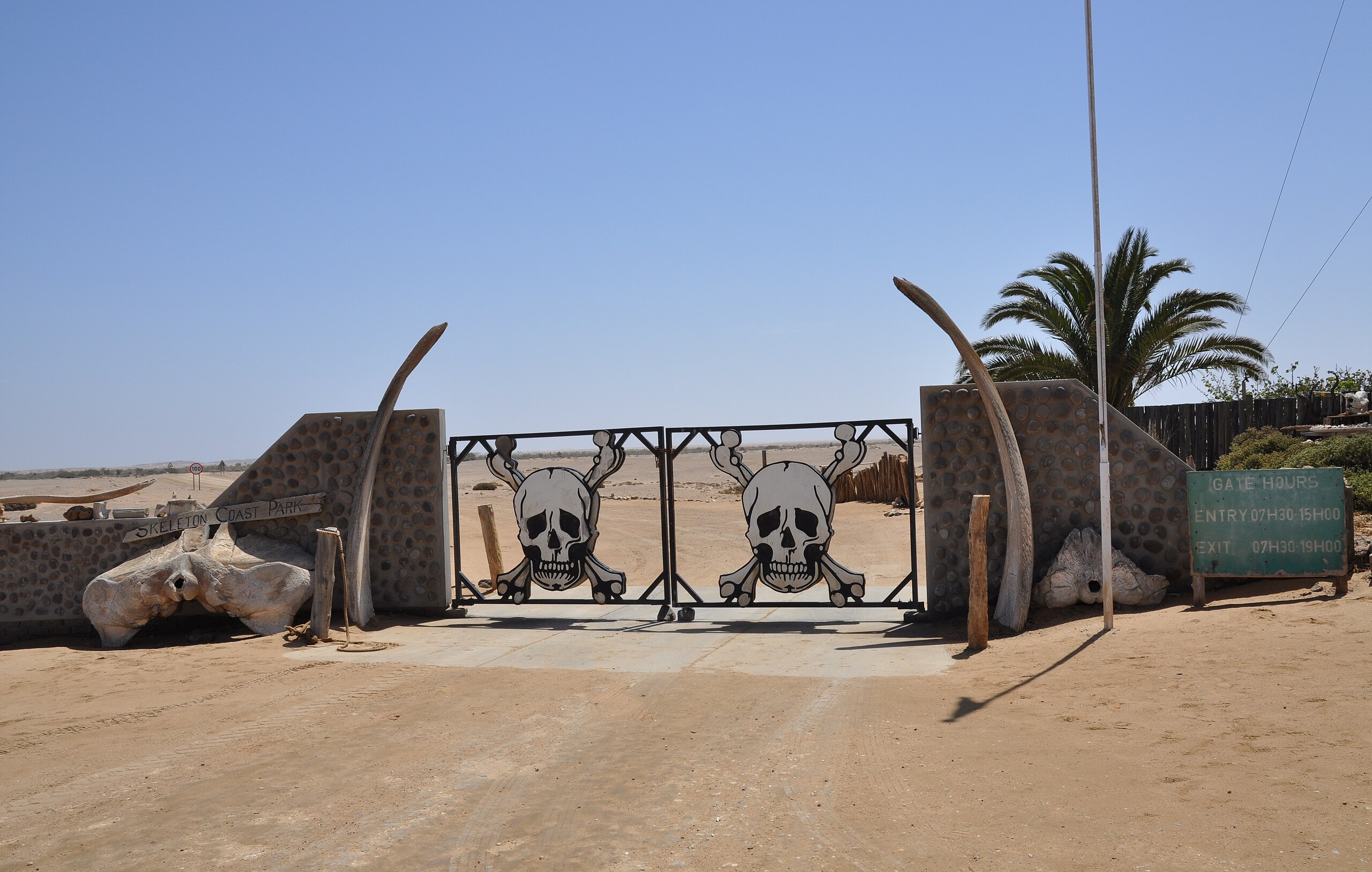 Southern Entrance to the Skeleton Coast National Park, Namibia, with gates decorated as a skull and crossbones and flanked by bleached whale bones