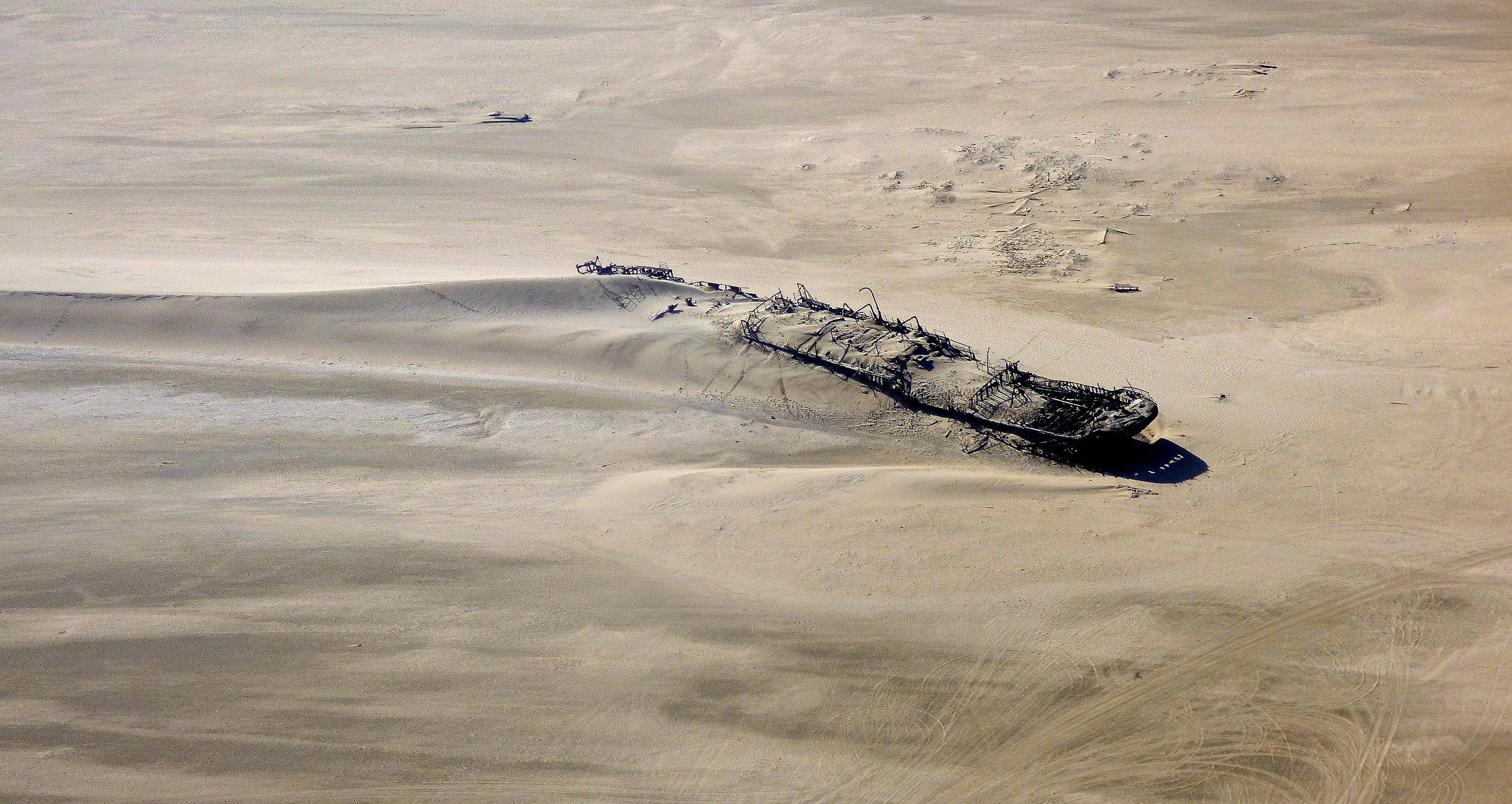 wrecked ship photographed from above, partially covered in sand