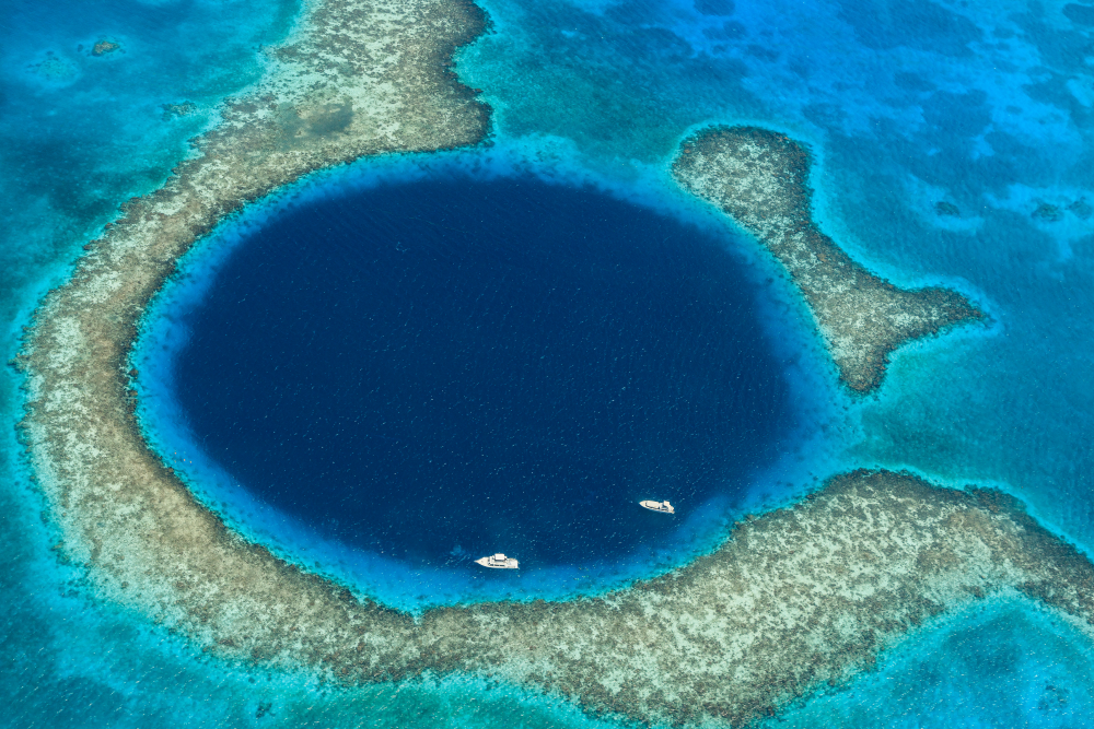 an aerial photograph of the great blue hole off the coast of belize with two boats on its surface