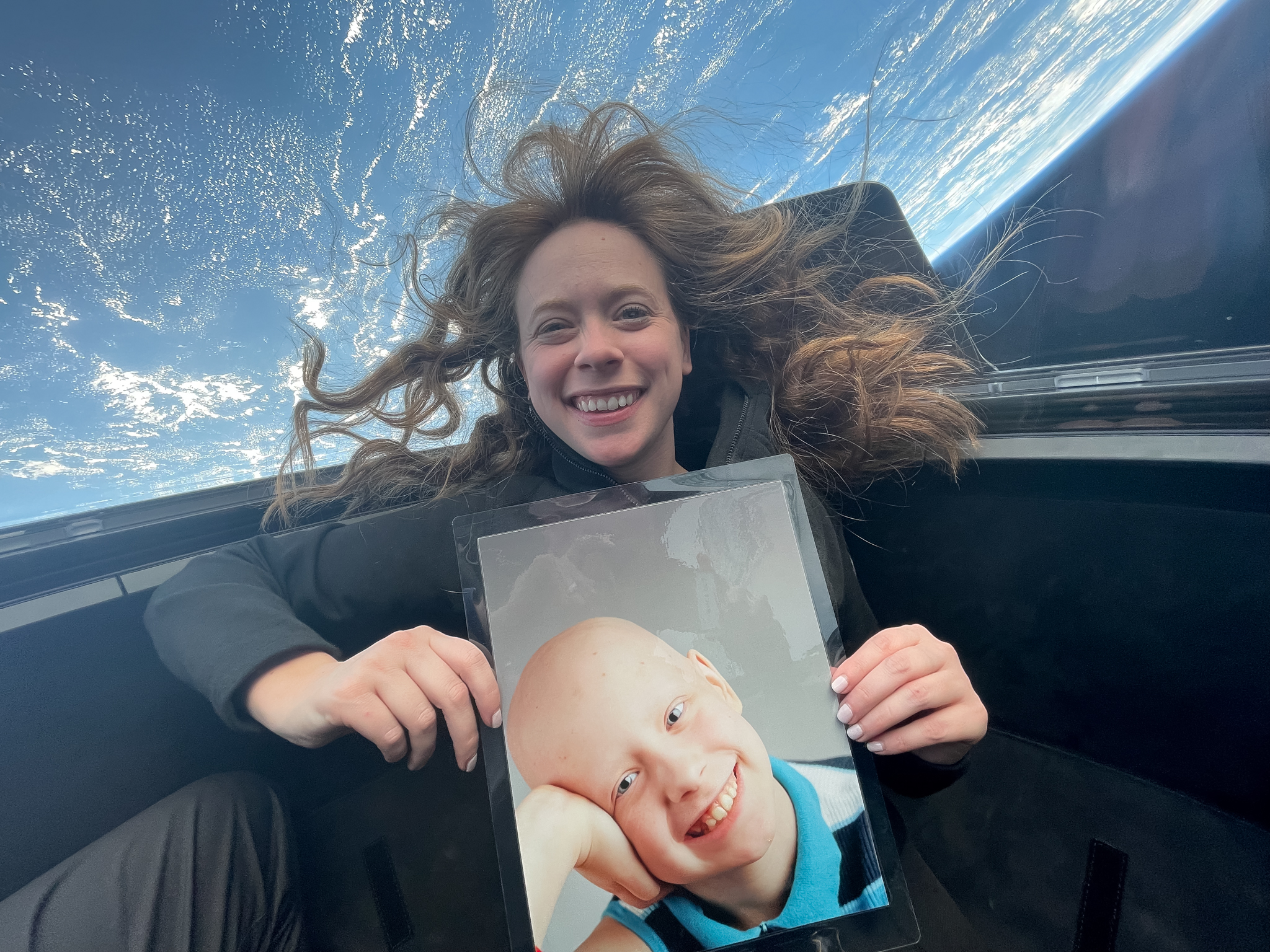 Hayley Arceneaux, chief medical officer for Inspiration4, photographed in space holding a photo of herself as a child while she was undergoing cancer treatment.