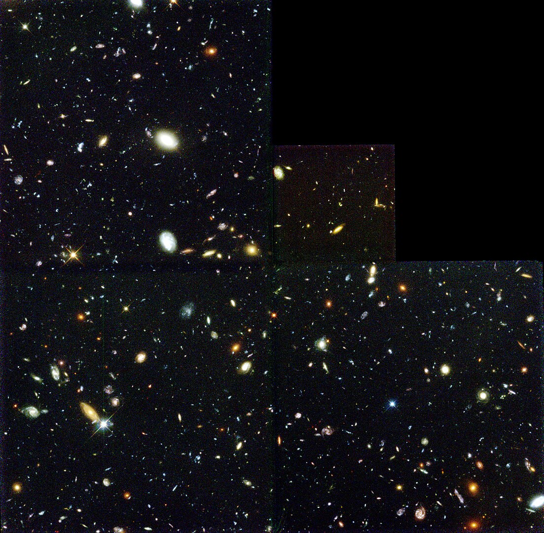 Apart for the top right corner, the image is a vast number of galaxies over the blackness of space. some are clearly visible while many others are just dots.