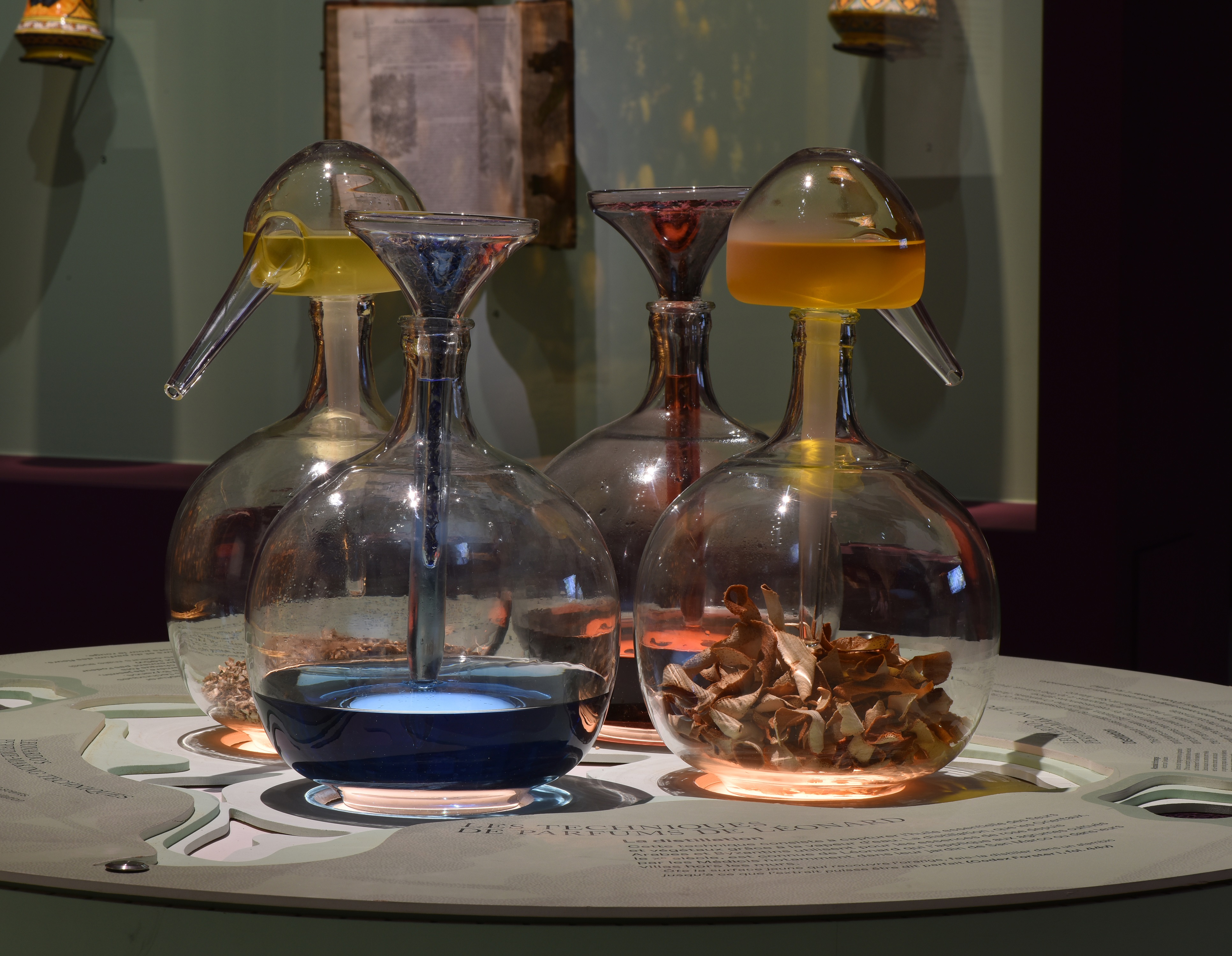 Glass distillery bottles showing how essential oils are distilled from water vapour and ingreditents like flower petals or citrus fruits.