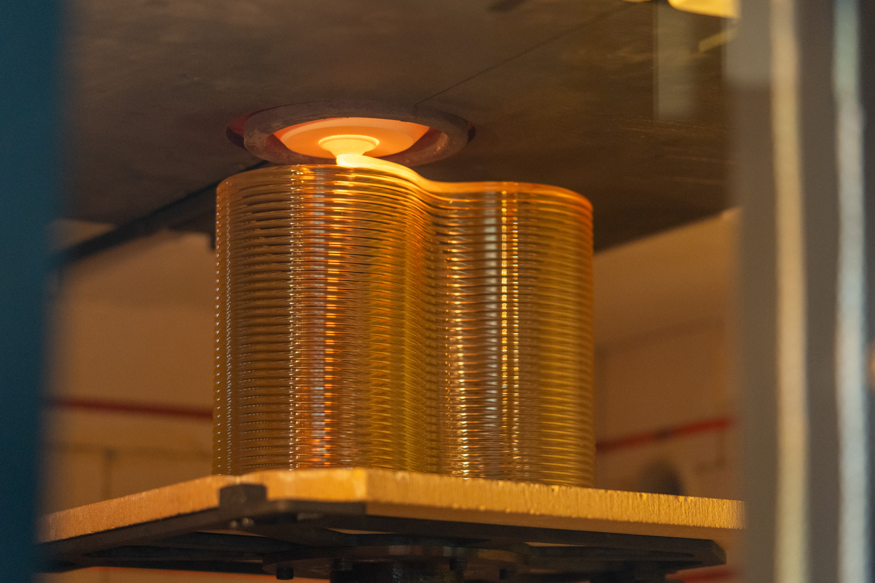 A glass brick, made of layers of glass in a figure 8 shape, being printed.