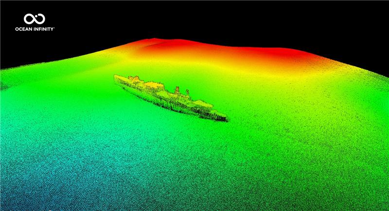 The image shows the multibeam scan of the ship resting on the sea floor. The image shows the seafloor in greens that become yellow and then red as the elevation rises. The ship sits in the middle of a large green patch and appears in one piece. 