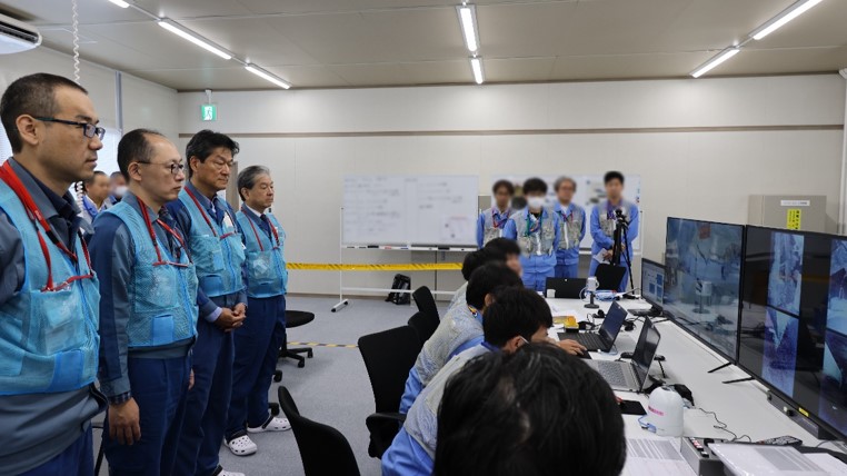 Workers at Fukushima watch the retrieval operation from the control room.