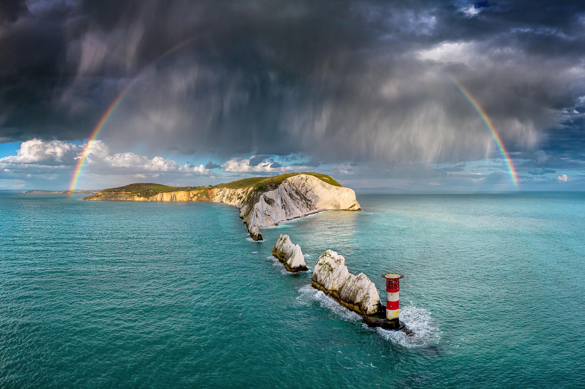 Beautiful photography of a rainbow and dark clouds over the coast of the UK.