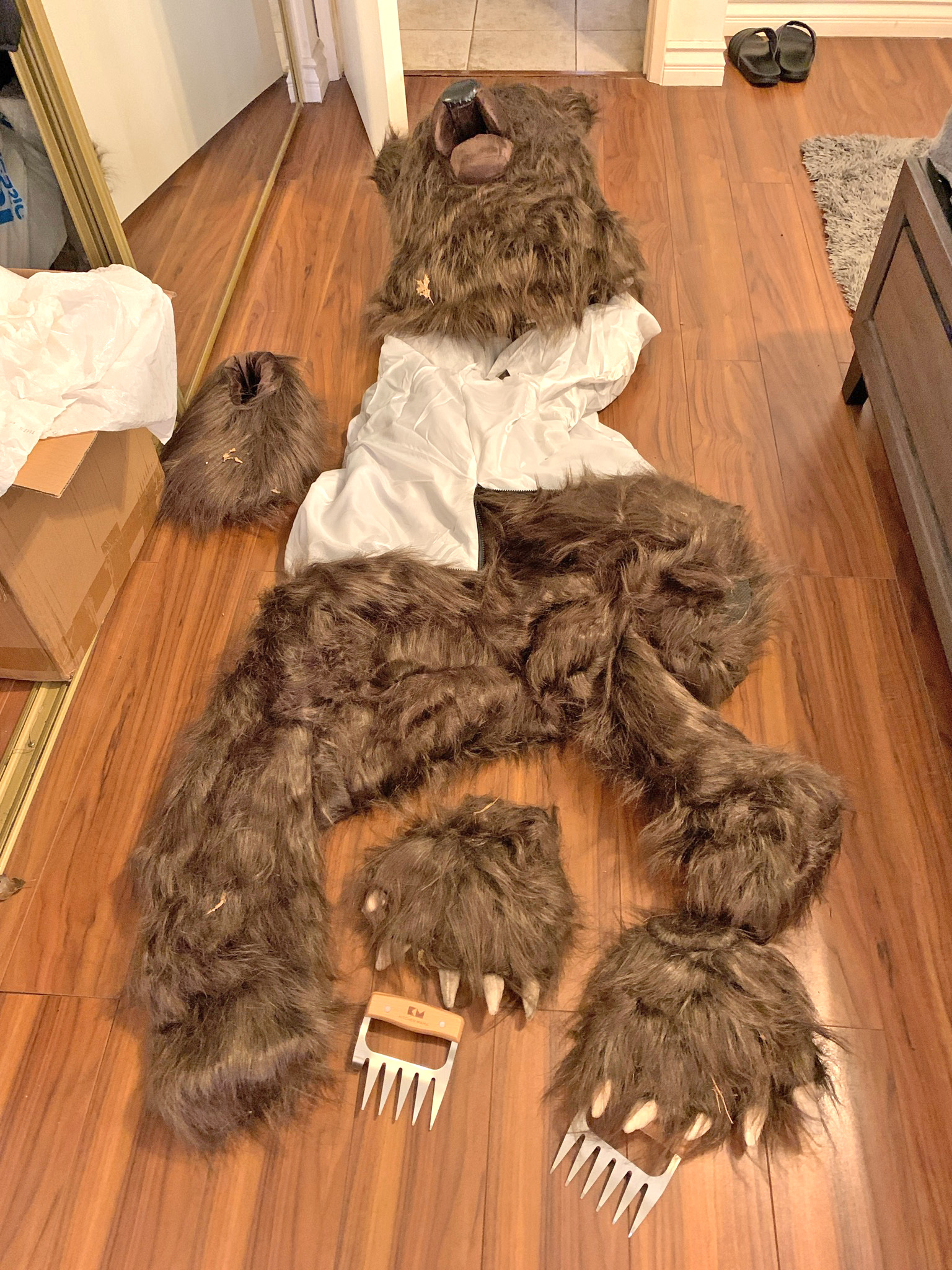 photograph of a bear costume laid out on a wooden floor