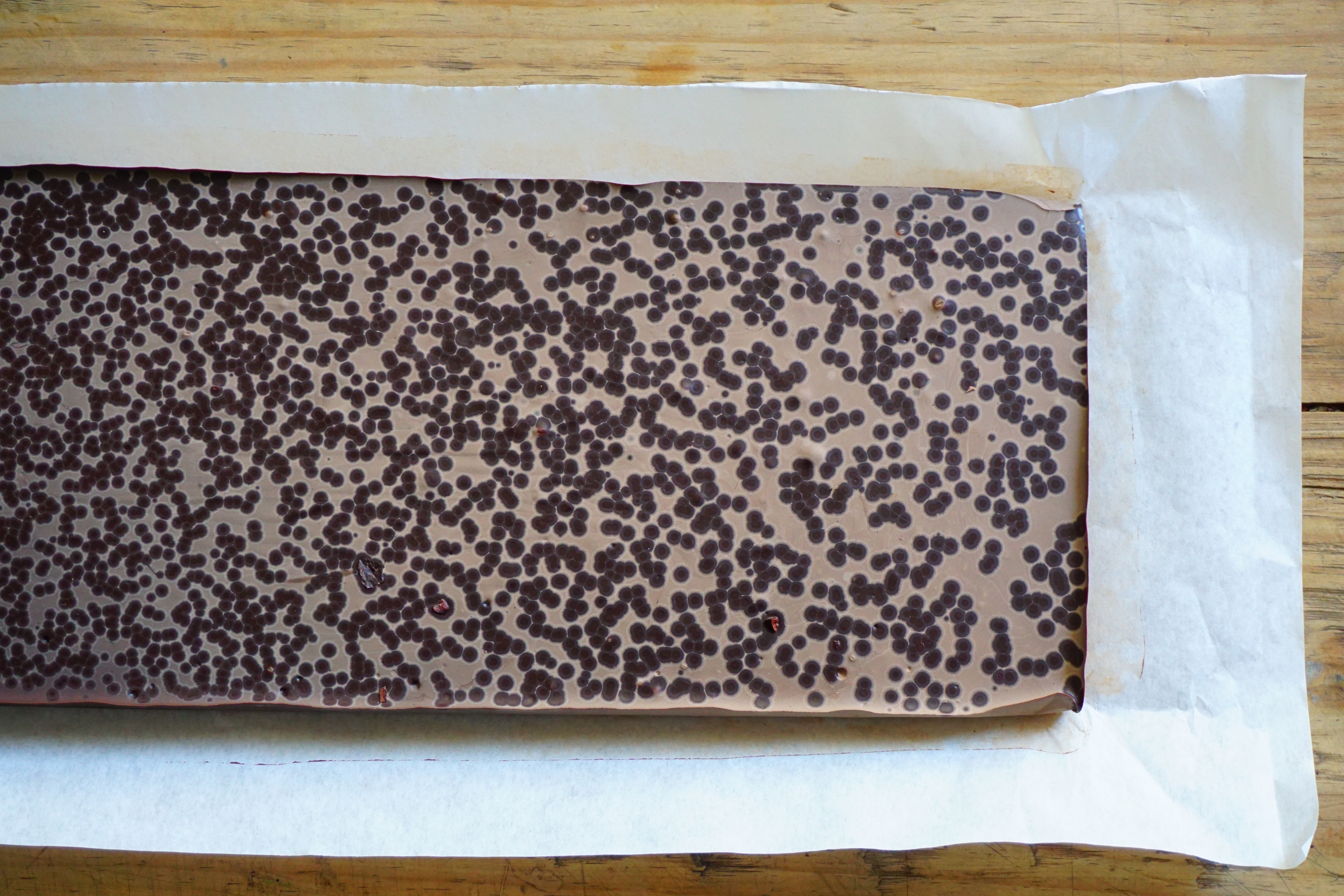 large areas of fat bloom on a bar of chocolate sitting on a piece of paper