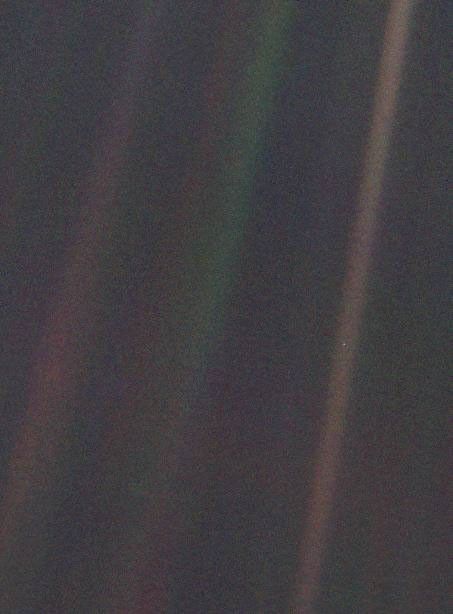 the image shows sunbeams. reflections on the camera, and in one of them a tiny dot is earth