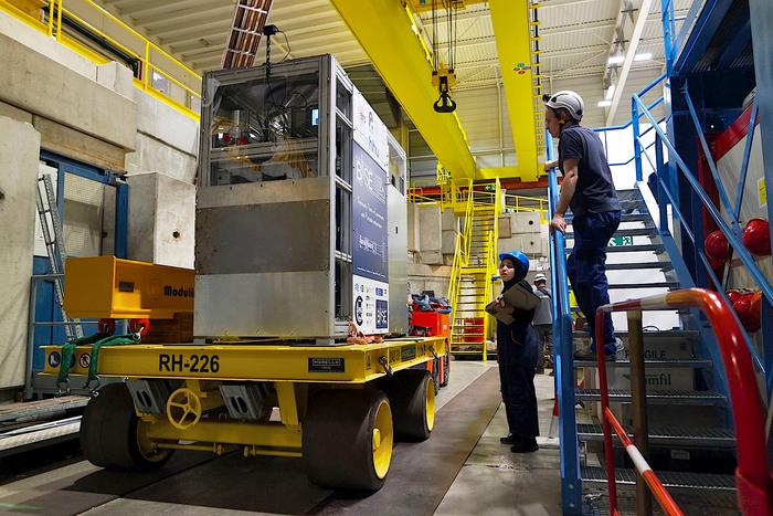 BASE-STEP on a transfer trolley. A metallic cuboided on a yellow four wheeled trolley