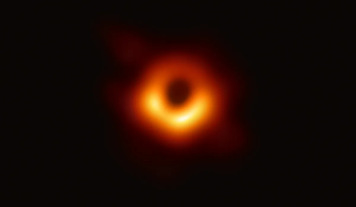 The event horizon telescope image ofM87*. An orange donut with some brighter spots is seen around a dark center where the black hole is The event horizon telescope image ofM87*. An orange donut with some brighter spots is seen around a dark center where the black hole is