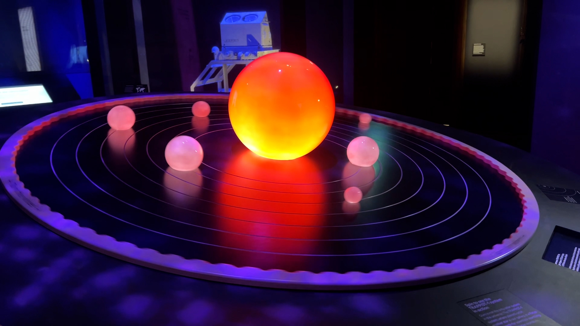 a slanted circular table. There is a large sphere in the middle, the star, and six other visible - the six out of seven planets that orbit the system a slanted circular table. There is a large sphere in the middle, the star, and six other visible - the six out of seven planets that orbit the system