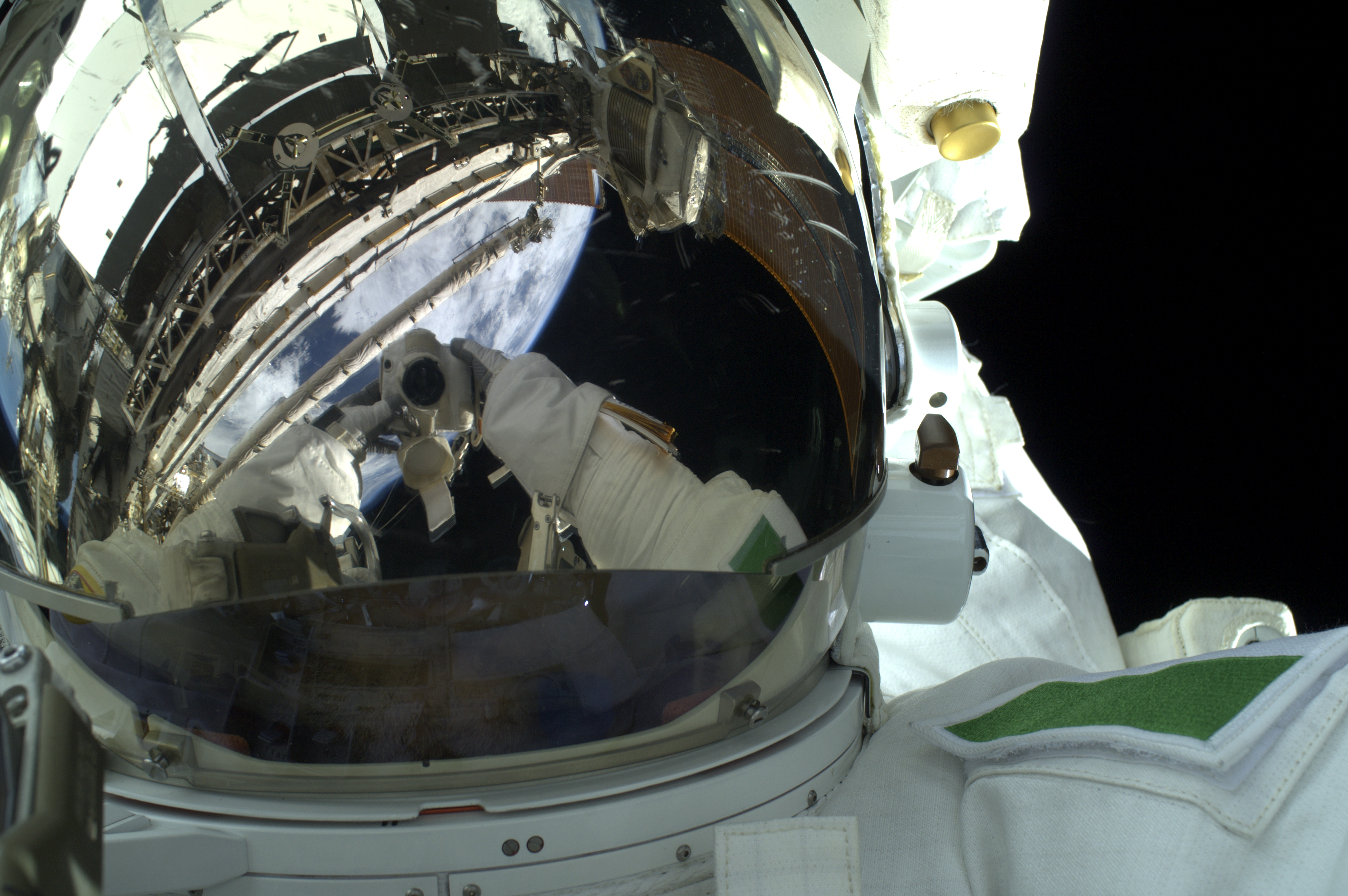 armitano has thereflective sunvisor pull donw so you can see the camera in it and behind the Earth. armitano has thereflective sunvisor pull donw so you can see the camera in it and behind the Earth.