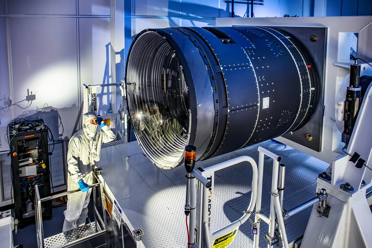 LSST Camera Deputy Project Manager Travis Lange shines a flashlight into the LSST Camera. The camera is a black cylinder much bigger than him LSST Camera Deputy Project Manager Travis Lange shines a flashlight into the LSST Camera. The camera is a black cylinder much bigger than him