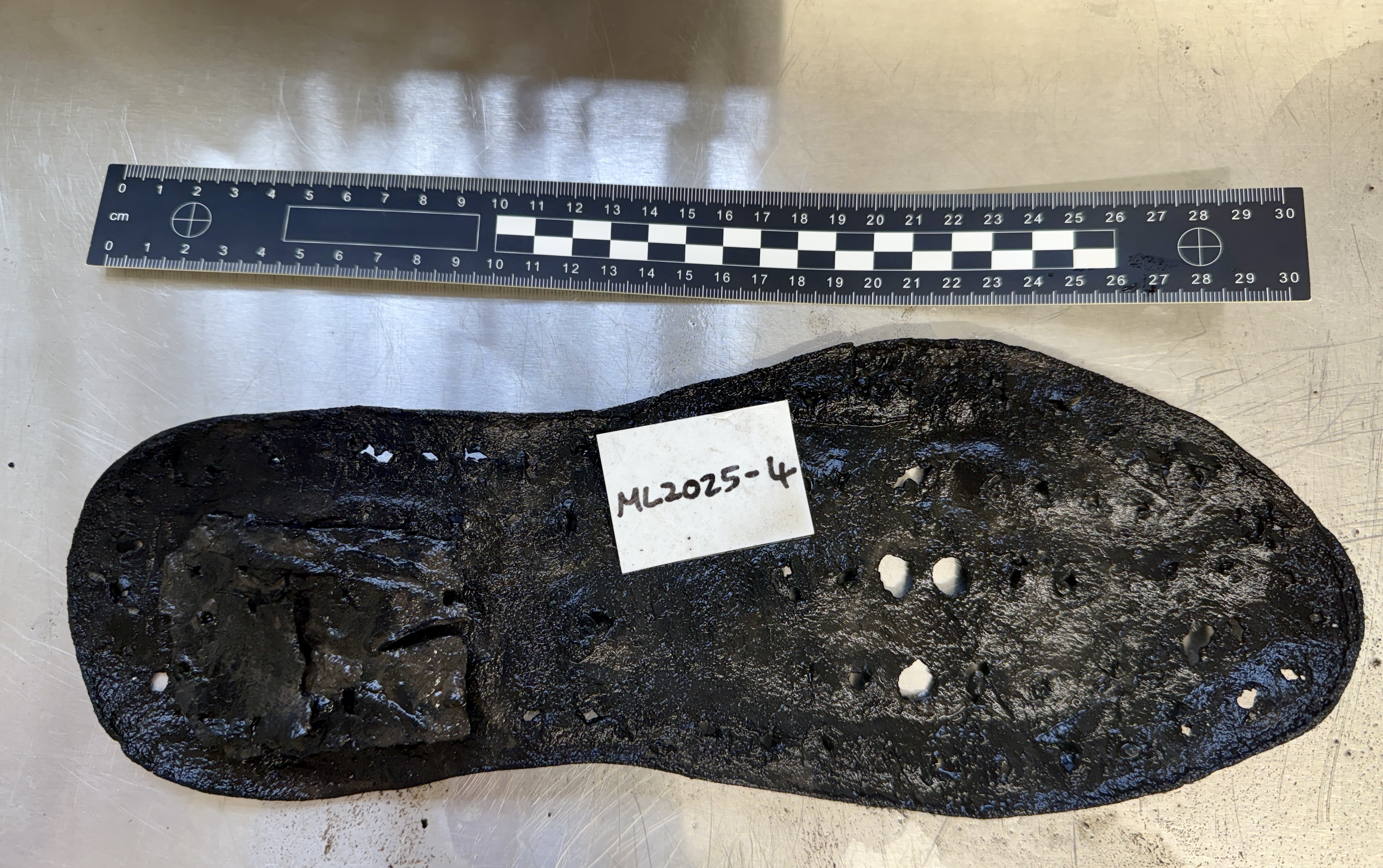 A shoe sole next to a 30 centimeter ruler . It is bigger than the ruler. A shoe sole next to a 30 centimeter ruler . It is bigger than the ruler.