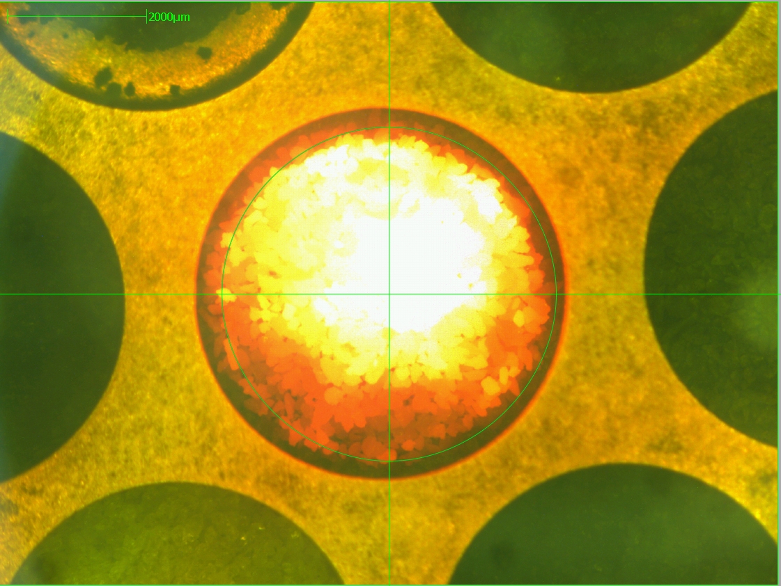 micrograph of rock samples being melted with a CO2 laser to release argon gas; the sample is in a circular well in the middle of the image and appears bright white in the centre, fading out to yellow and red at thee edges. It's in the centre of a green crosshair. micrograph of rock samples being melted with a CO2 laser to release argon gas; the sample is in a circular well in the middle of the image and appears bright white in the centre, fading out to yellow and red at thee edges. It's in the centre of a green crosshair.