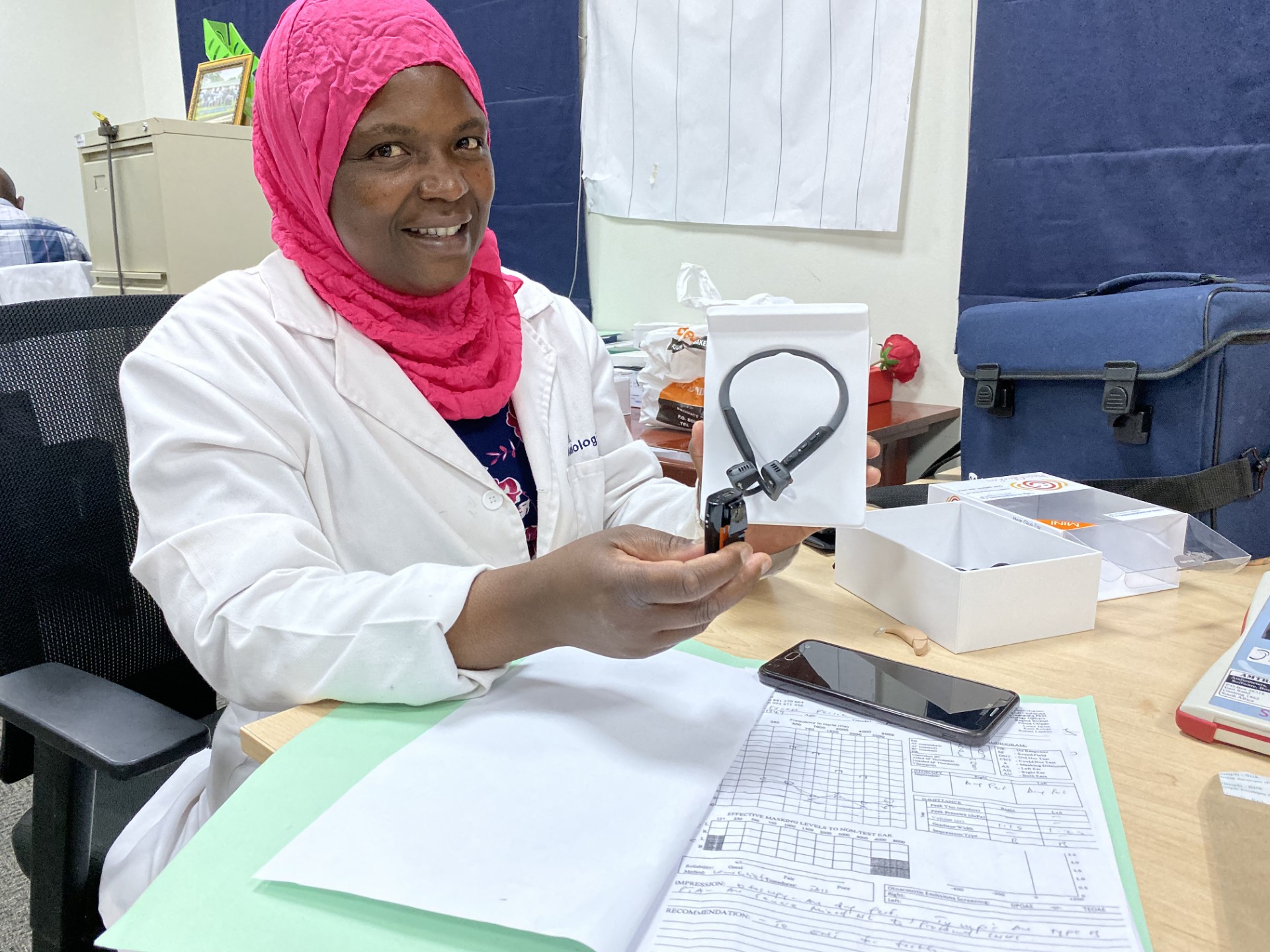Mwanaisha Phiri, lead audiologist in Malawi (wearing a pink headscarf and a white lab coat) with the bone conducting hearing aide for the first time Mwanaisha Phiri, lead audiologist in Malawi (wearing a pink headscarf and a white lab coat) with the bone conducting hearing aide for the first time