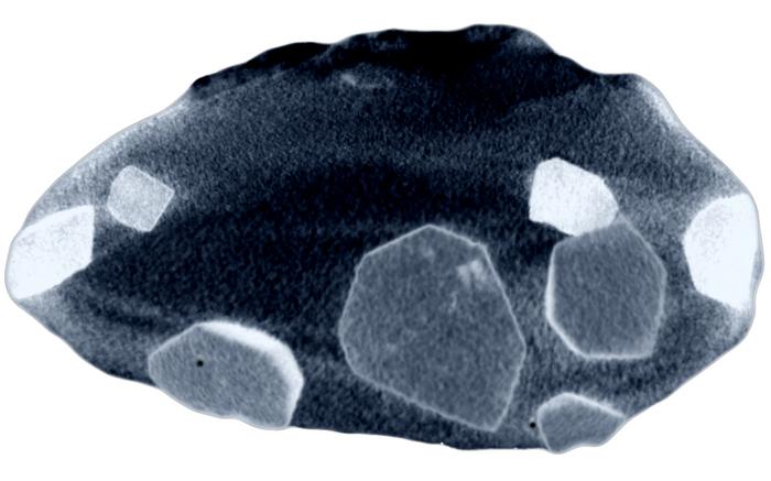 a grainy image of a chonky nugget with flat poligonal crystals in it.